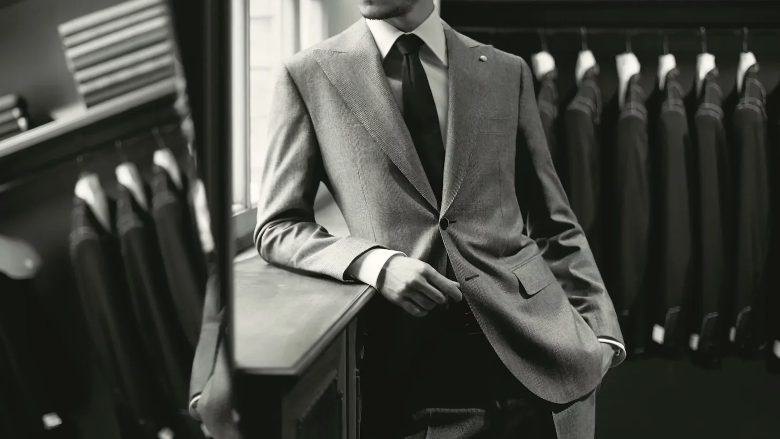 a man in suit in front of a row of jackets